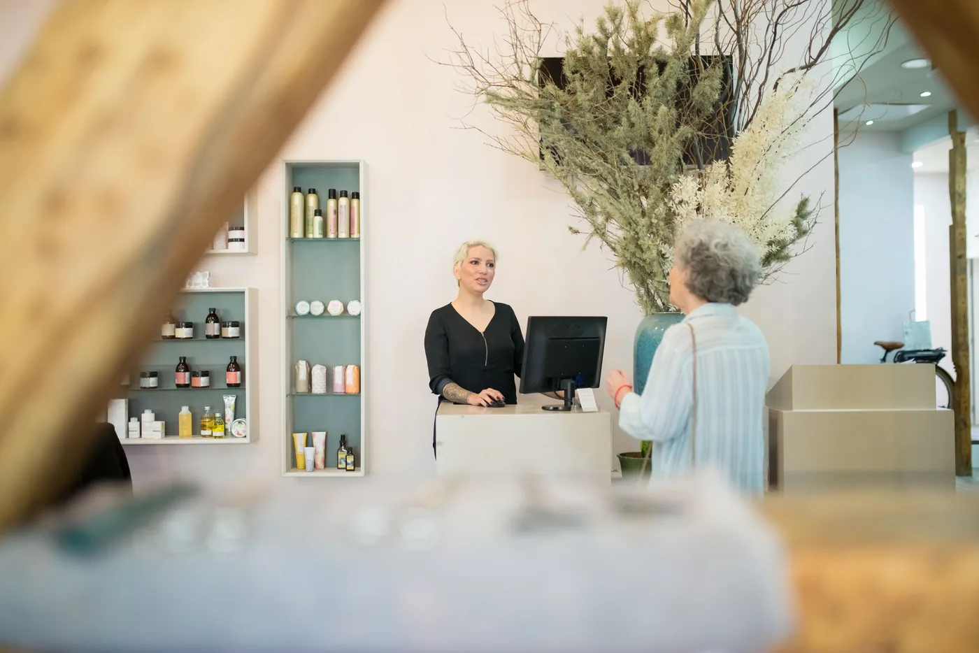 Empfang eines Coiffeursalons: eine Kundin spricht mit der Mitarbeiterin am Tresen, dahinter der Bildschirm mit dem Terminkalender.
