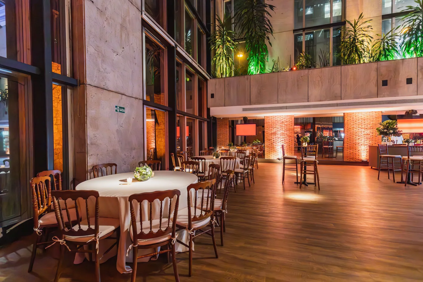 Restaurant am Abend: gedeckte runde Tische mit Holzstühlen und warmem Licht, die Gäste sind noch nicht da.